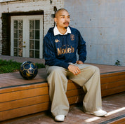 Male model wearing Ahop Modelo Hoodie in navy blue and gold. Front view.
