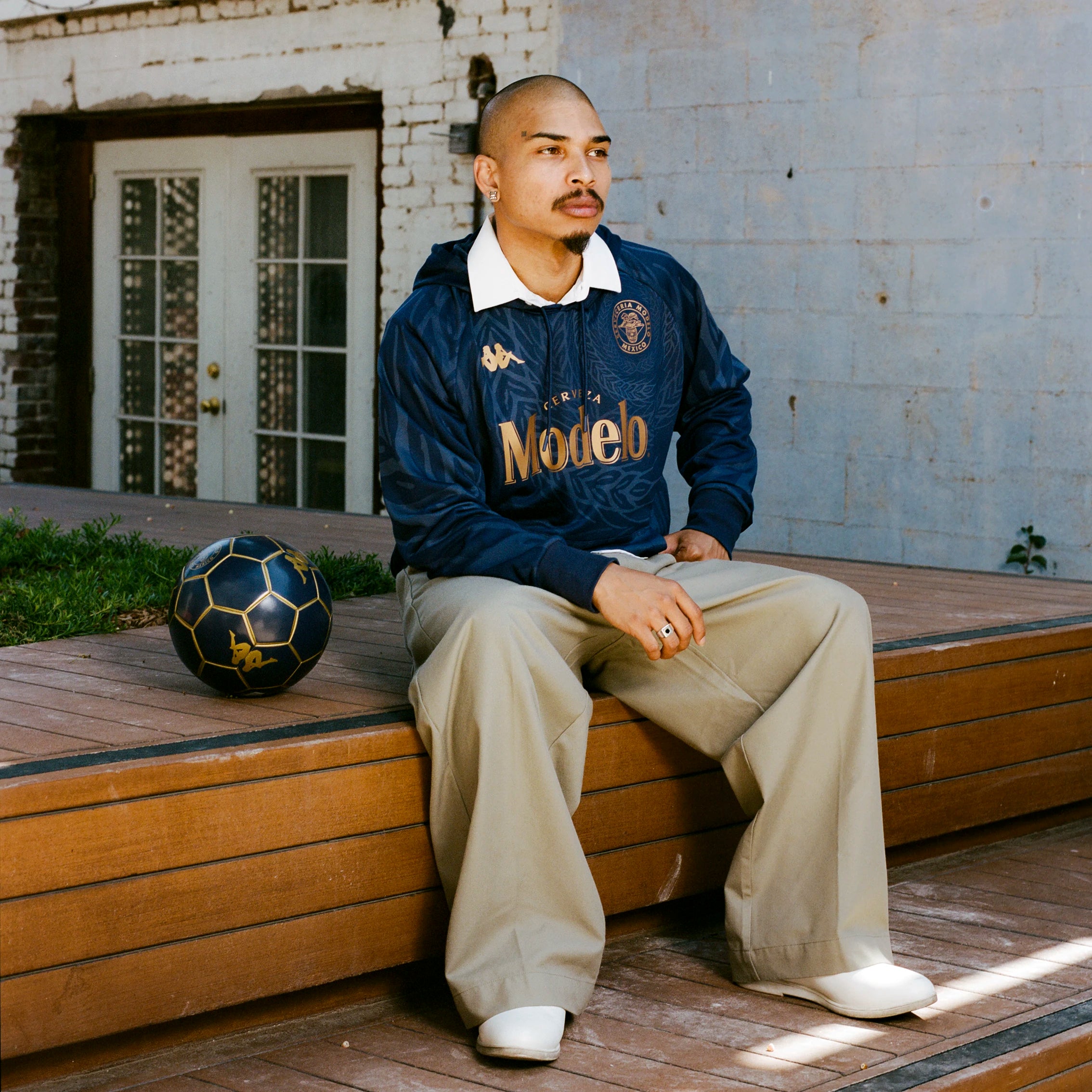 Male model wearing Ahop Modelo Hoodie in navy blue and gold. Front view.