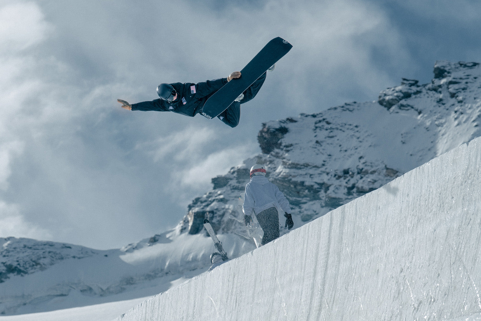 US Snowboarder pops a trick in the air on the slope in official US Kappa gear. 