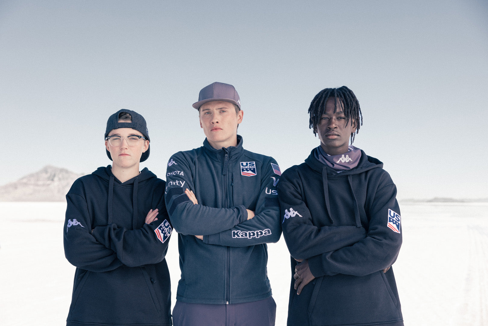 Group shot of three Male US athletes looking directly at camera in full Kappa X US apparel 