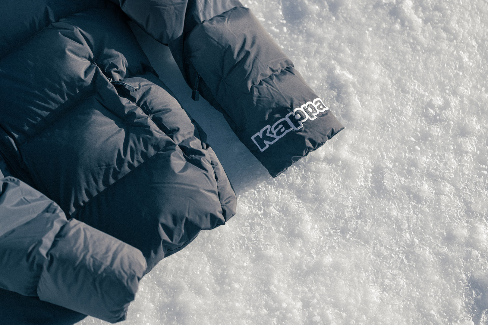 Extreme close up of Kappa puffer jacket on salt flats with Kappa Logo in focus. 