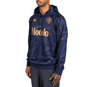 Male model wearing Ahop Modelo Hoodie in navy blue and gold. Side view.