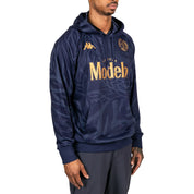 Male model wearing Ahop Modelo Hoodie in navy blue and gold. Side view.