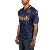 Male model wearing Kombat 2025 Modelo Soccer Jersey in navy blue and gold. Side view.