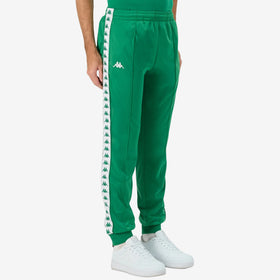 Man wearing Green Kappa track pants featuring Kappa Banda on side of legs in white and green. White Omini logo on right leg. Front side view.