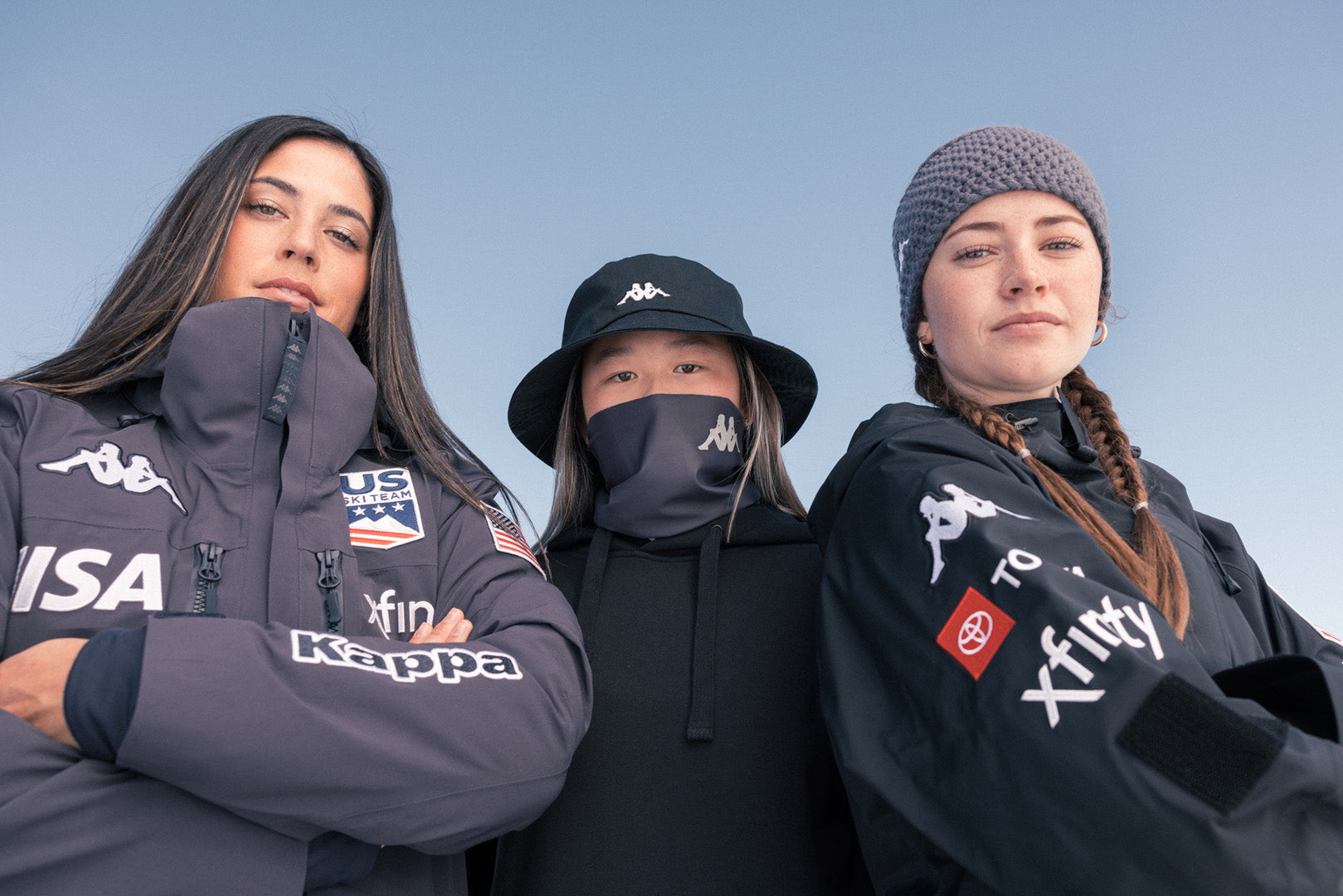 Group shot of three Female US athletes looking down at camera in full Kappa X US apparel 