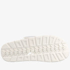 A close-up, top-down view of a white textured shoe sole with geometric tread patterns, set against a solid white background.