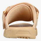 A close-up rear view of a beige slip-on sandal with a padded upper and thick textured sole, shown on a white background.