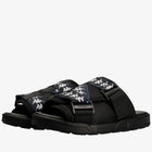 A pair of Kappa slide sandals in black with navy blue straps featuring the white Kappa logo pattern, shown on a clean white background.