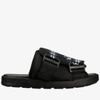 A black slide sandal with a wide strap featuring a navy blue and white graphic pattern, set against a plain white background.