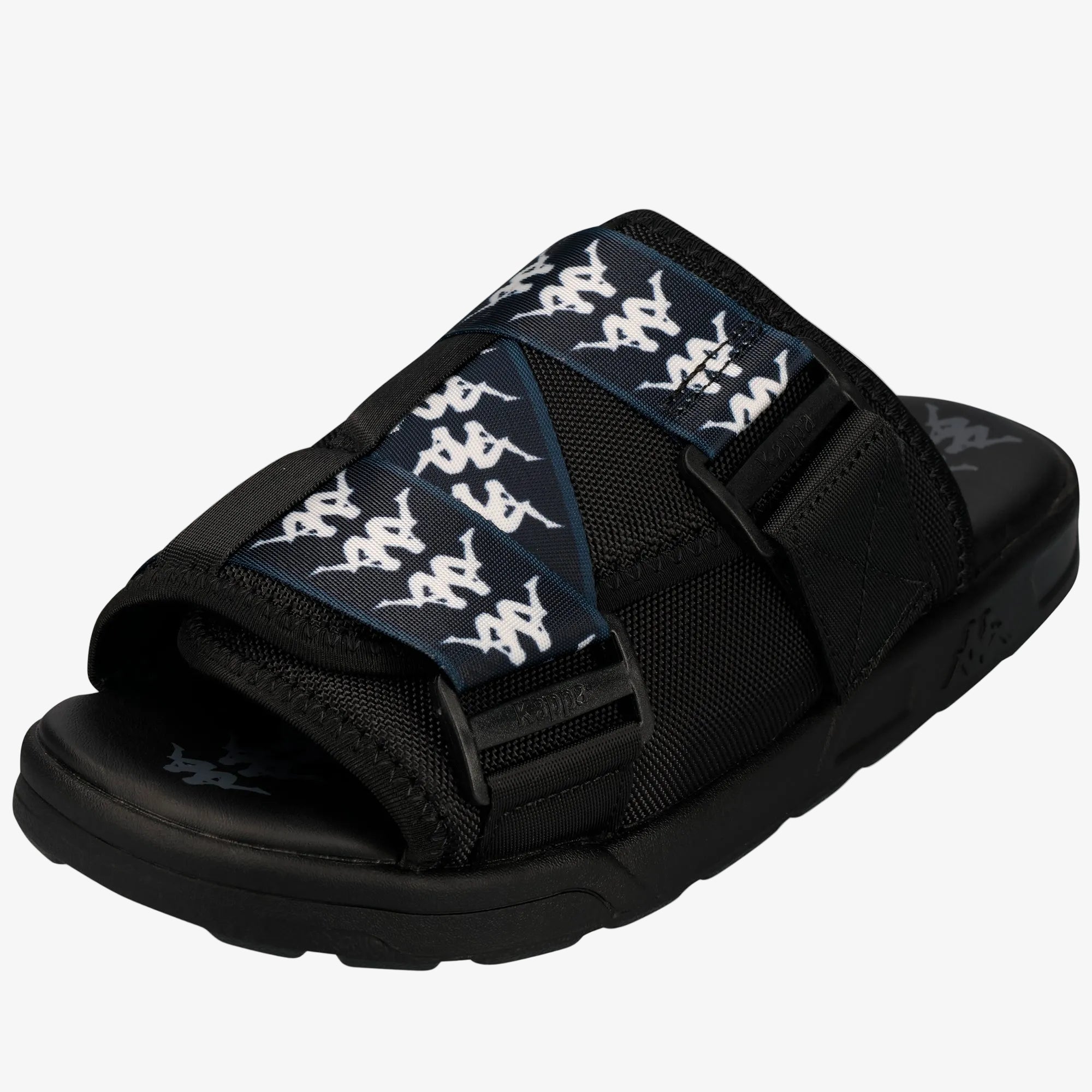 A black Kappa slide sandal with a wide black strap featuring a repeating white Kappa logo pattern, set against a plain white background.