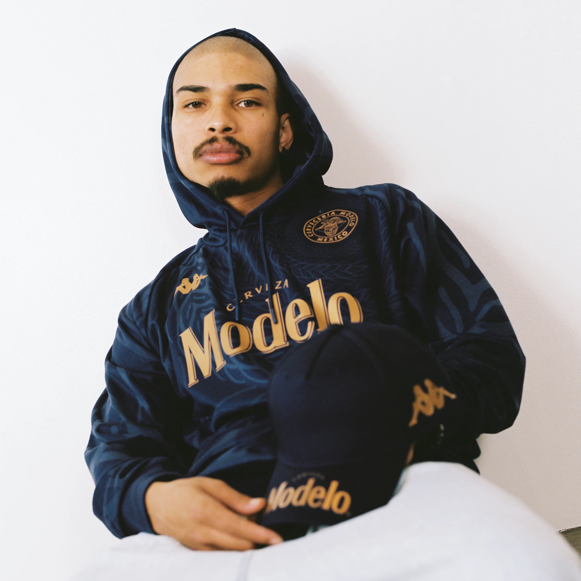 Male model wearing Ahop Modelo Hoodie in navy blue and gold. Front view.