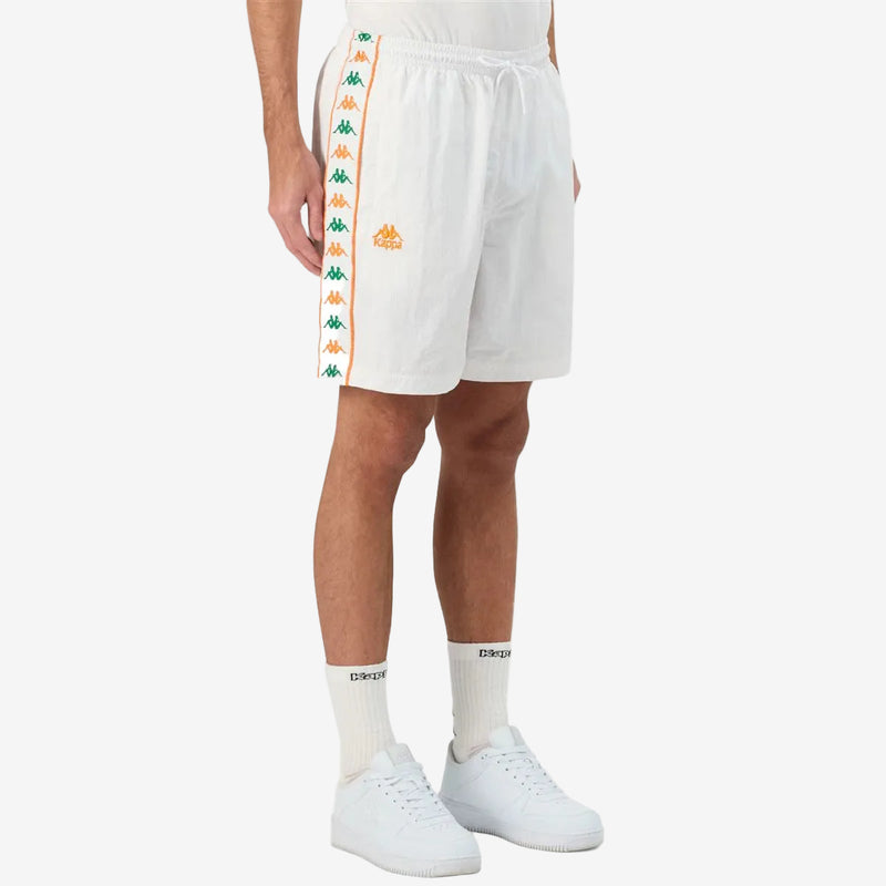 Man wearing white shorts featuring Kappa Banda on the sides with green and orange omini logos. Side view.
