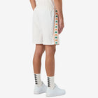 Man wearing white shorts featuring Kappa Banda on the sides with green and orange omini logos. Back view.