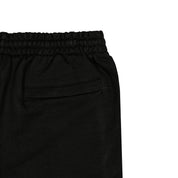 Detail view of back pocket of black shorts.