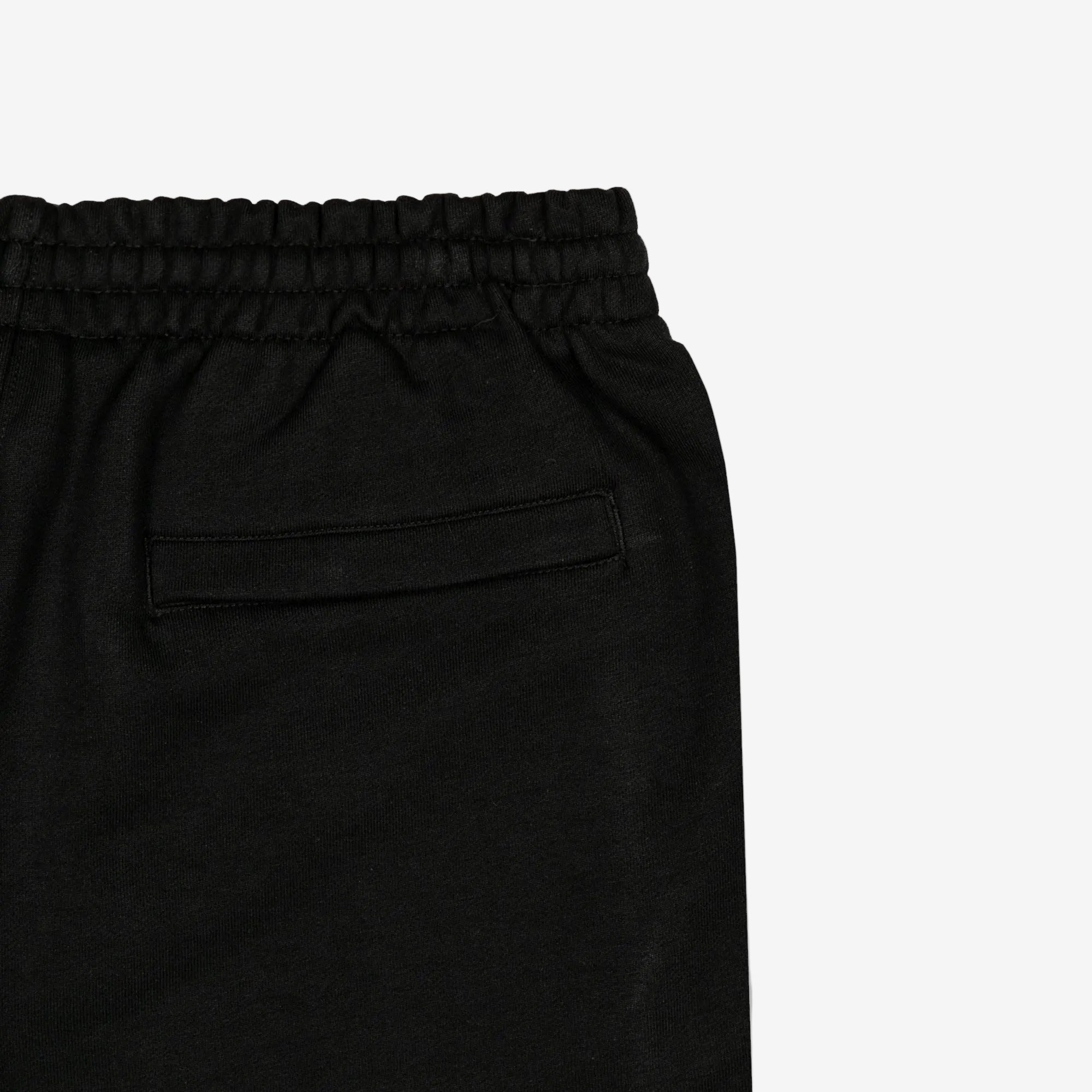 Detail view of back pocket of black shorts.