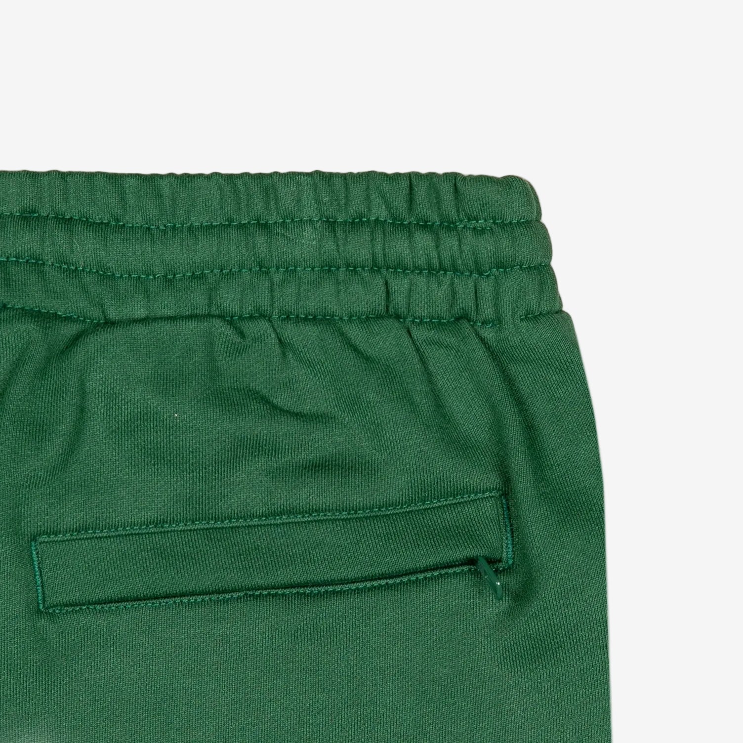 Detail view of back pocket of green shorts.