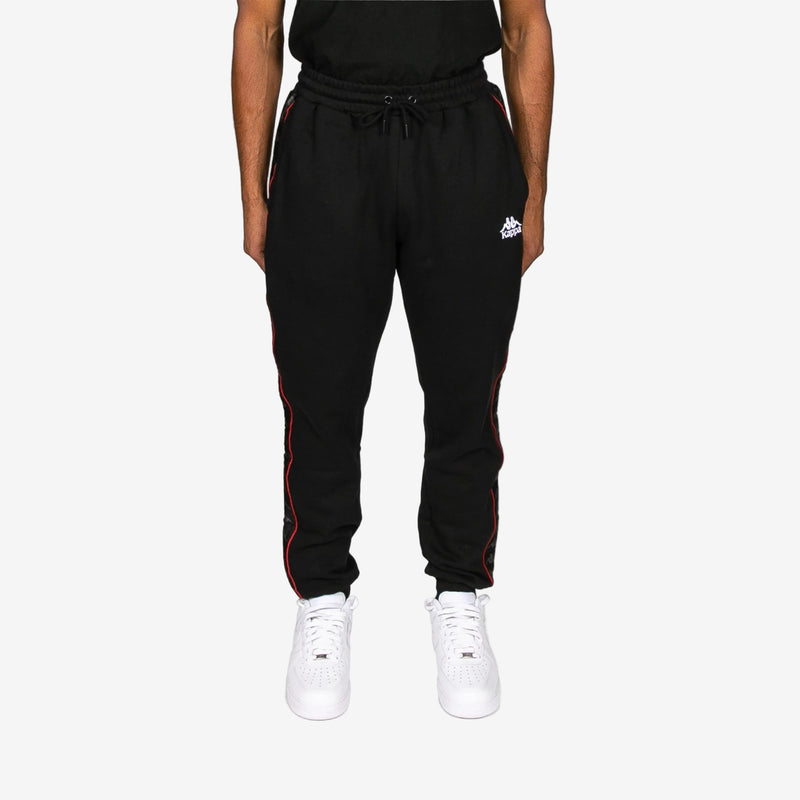 Black jogger pants with red accents worn by a person on a white background