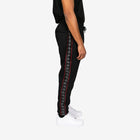Black jogger pants with red and white striped side panels worn by a person on a white background