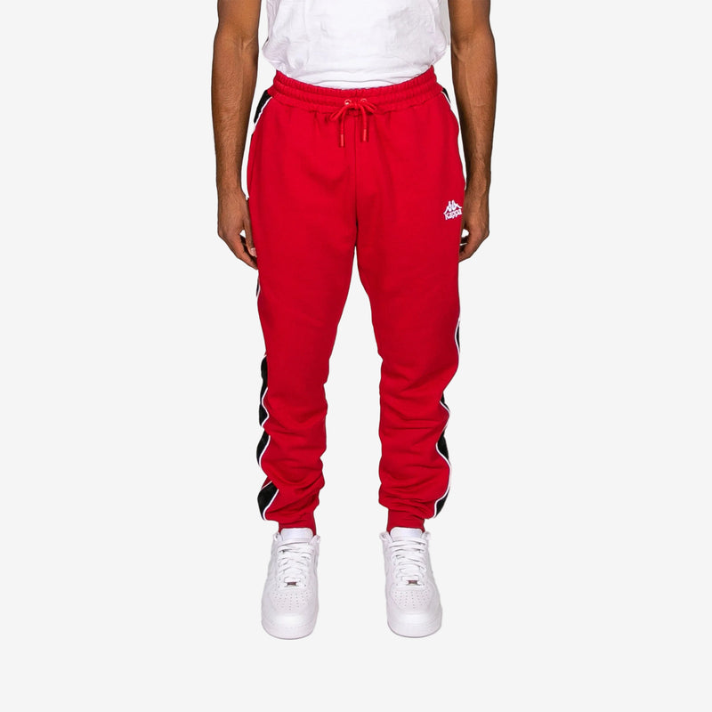 Red sweatpants with a brand logo worn by a person on a white background