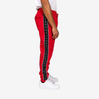 Red tracksuit pants with black side stripe worn by a person on a white background
