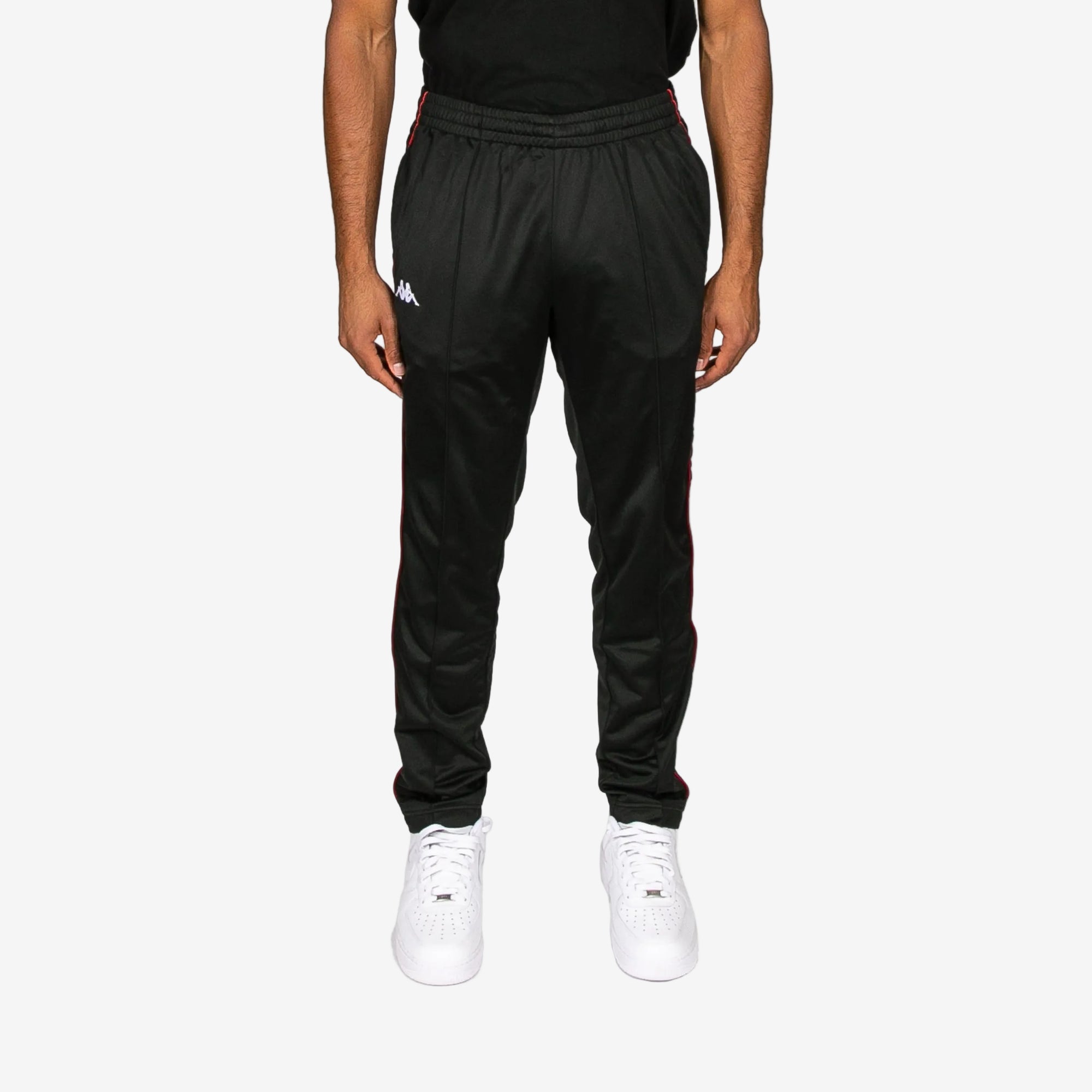 Person wearing black tracksuit pants with a brand logo on a white background