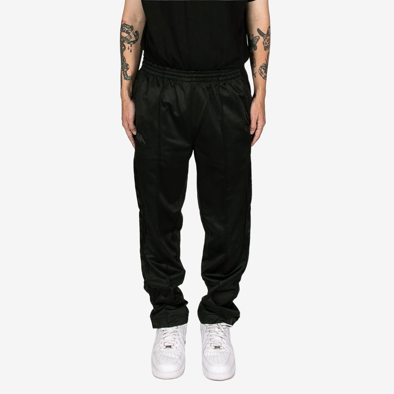 Person wearing black pants and white sneakers on a white background