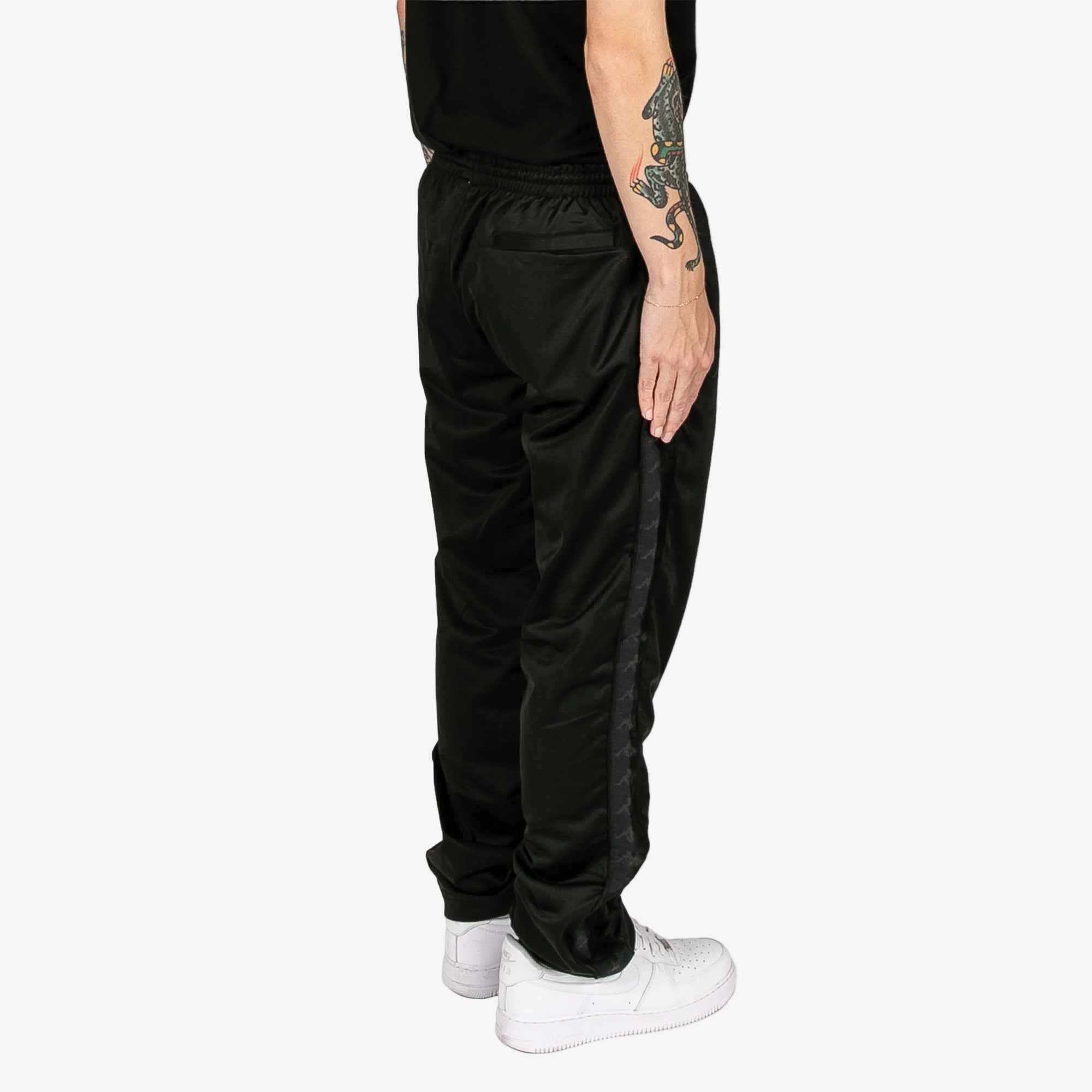 Person wearing black pants and white sneakers on a white background