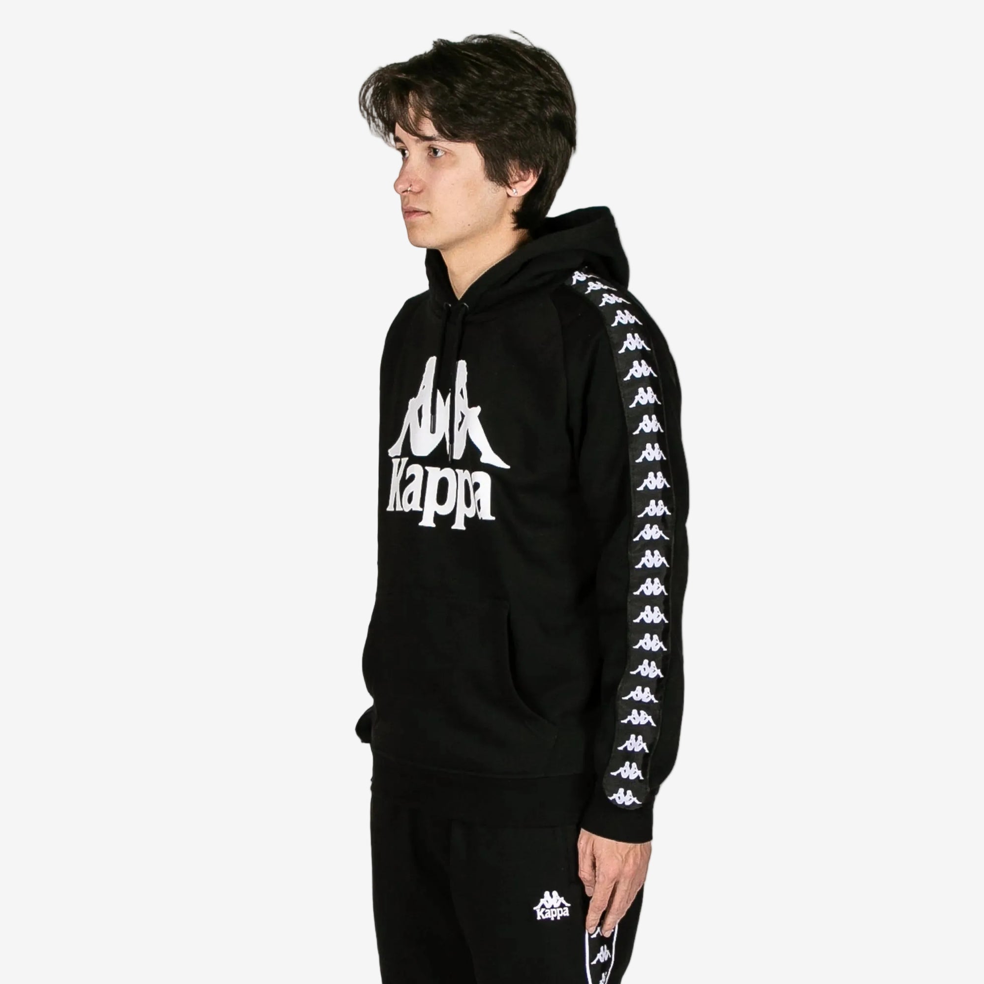 Person wearing a black Kappa hoodie with white branding on a white background