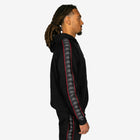 Person wearing a black hoodie with a patterned sleeve on a white background