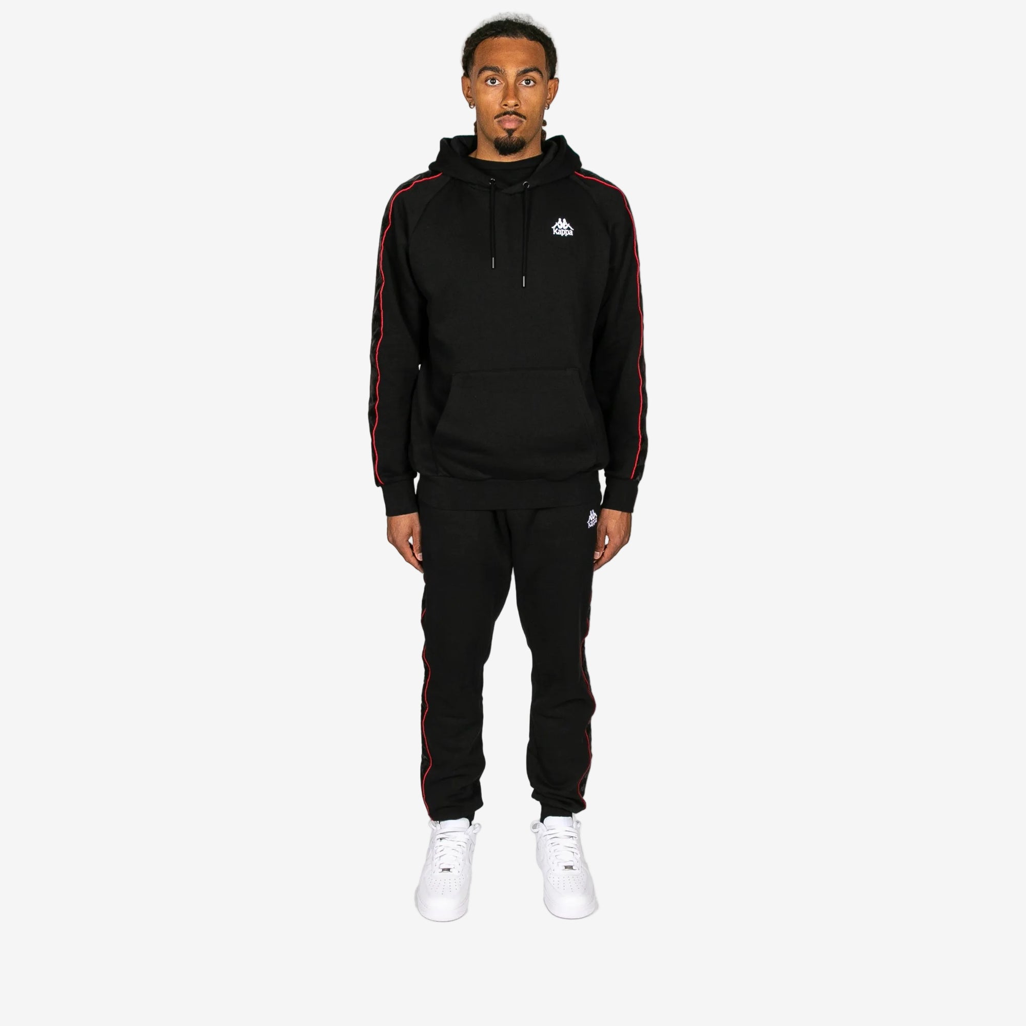 Person wearing a black tracksuit with red stripes on a white background