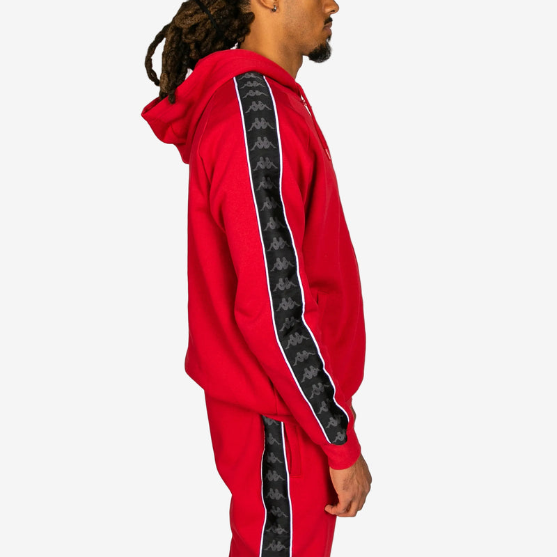 Red tracksuit with black patterned side panels worn by a person on a white background