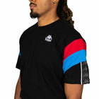 Person wearing a black Kappa t-shirt with red and blue sleeves on a white background