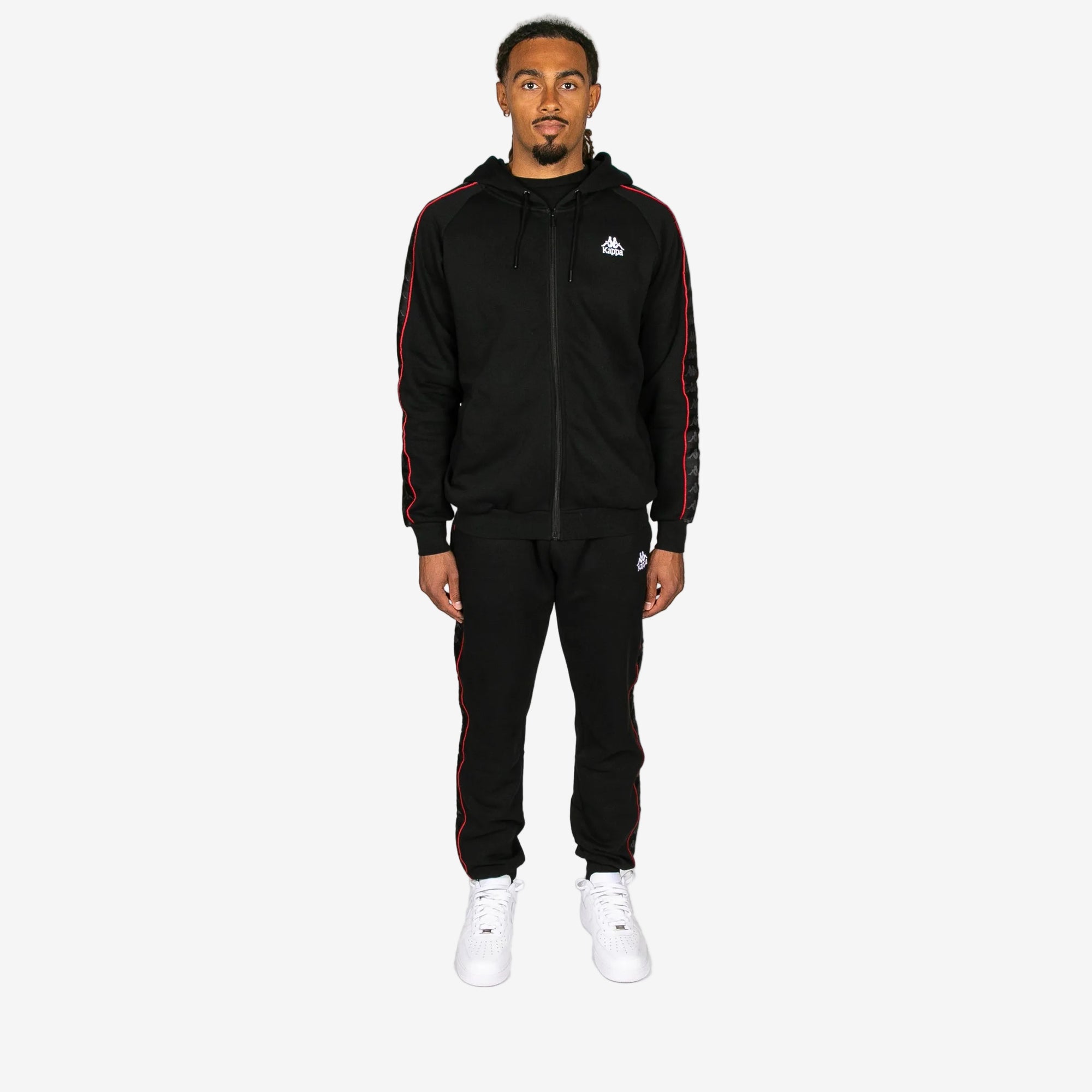 Man wearing a black tracksuit with red stripes on a white background
