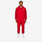 Person wearing a red Adidas tracksuit on a white background