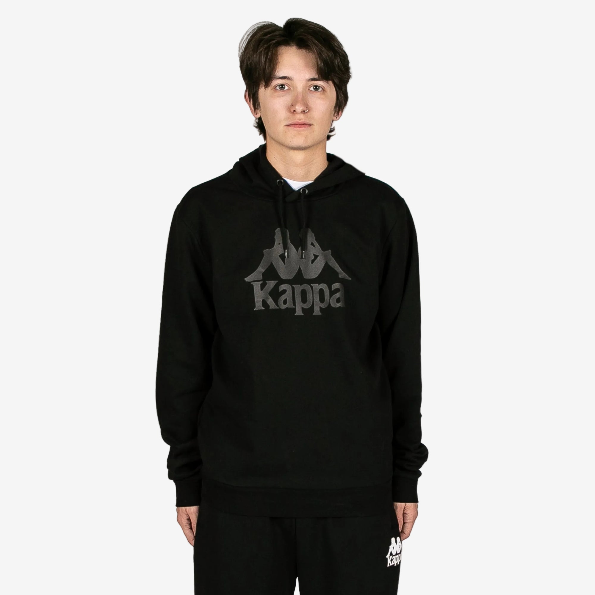 Person wearing a black Kappa hoodie on a white background