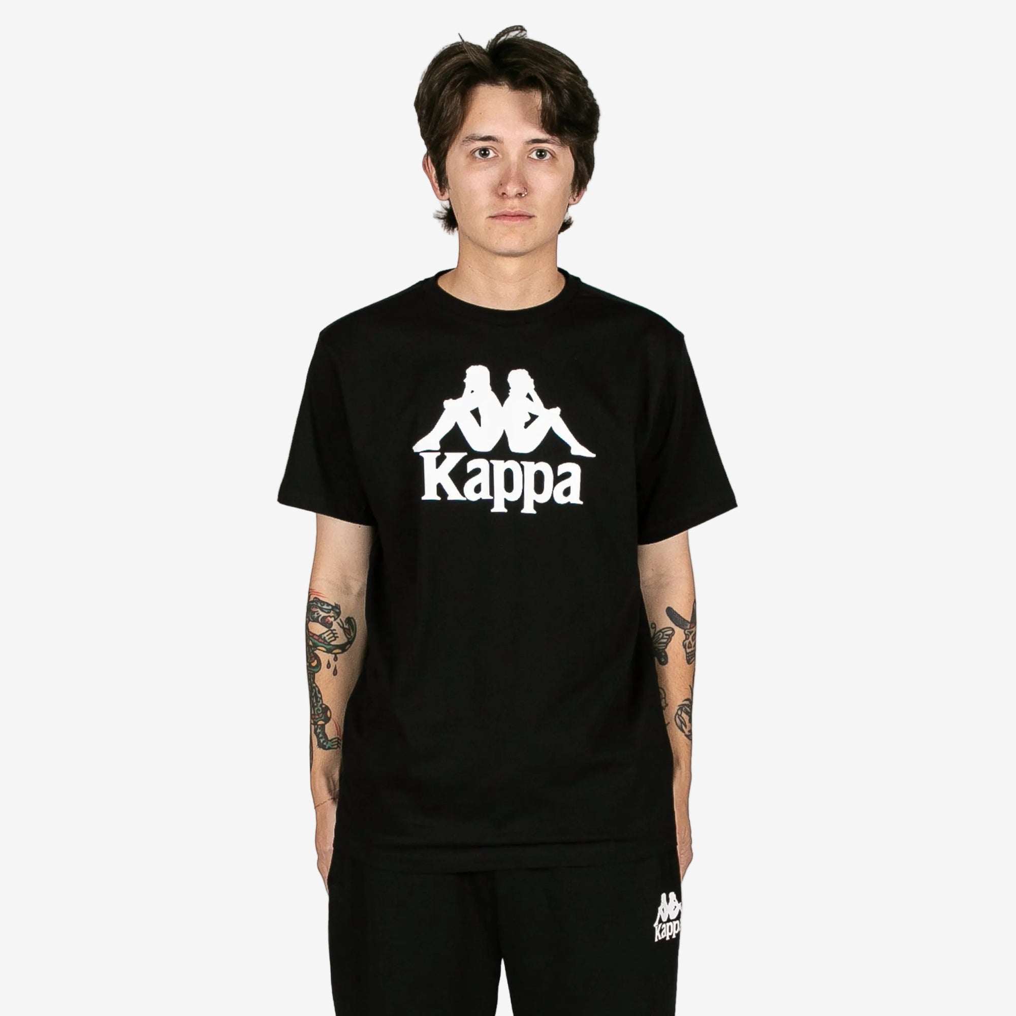 Person wearing a black Kappa t-shirt with a white logo on a white background