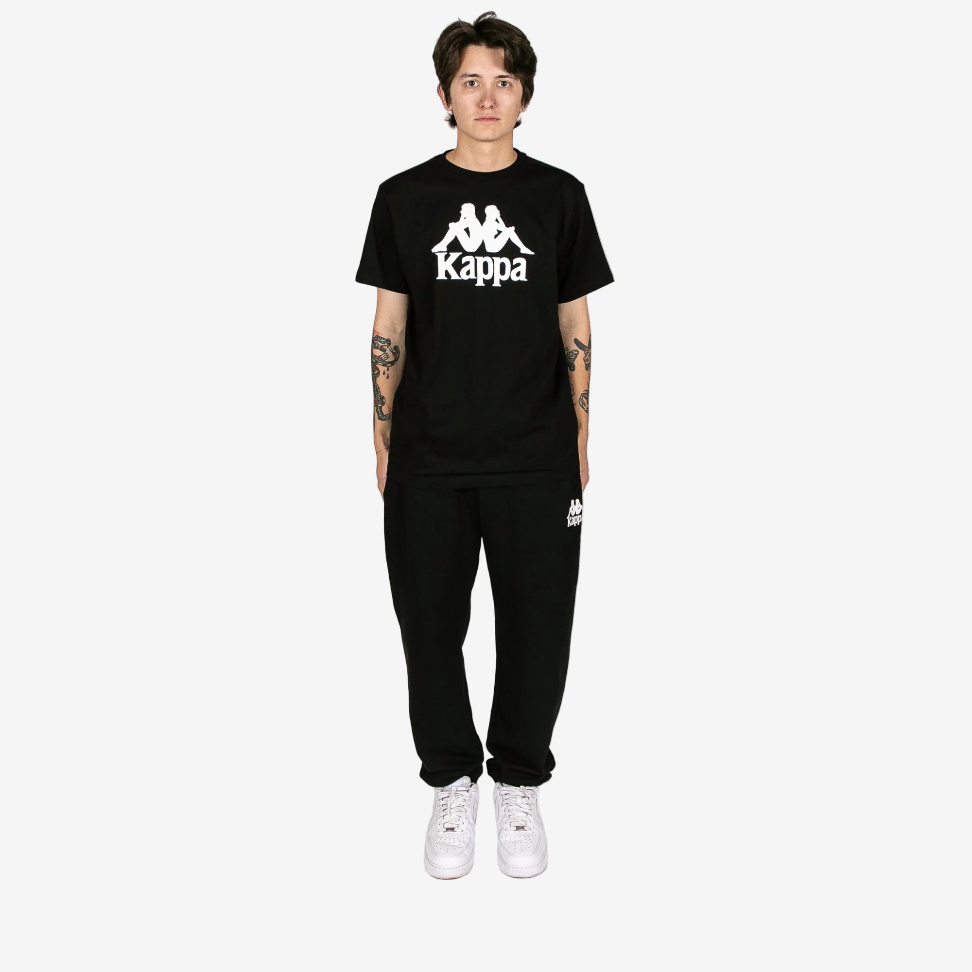 Person wearing a black Kappa t-shirt and pants on a white background