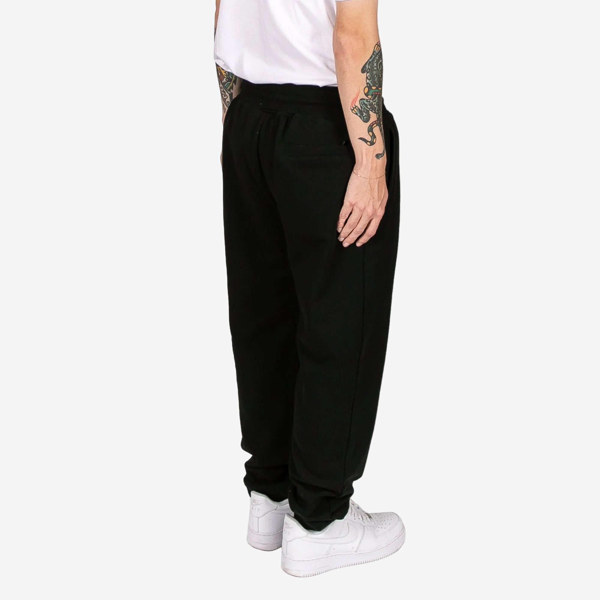 Person wearing black pants and white sneakers on a white background