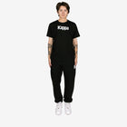 Person wearing a black Kappa t-shirt and pants on a white background