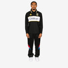 Person wearing a black tracksuit with brand logos on a white background