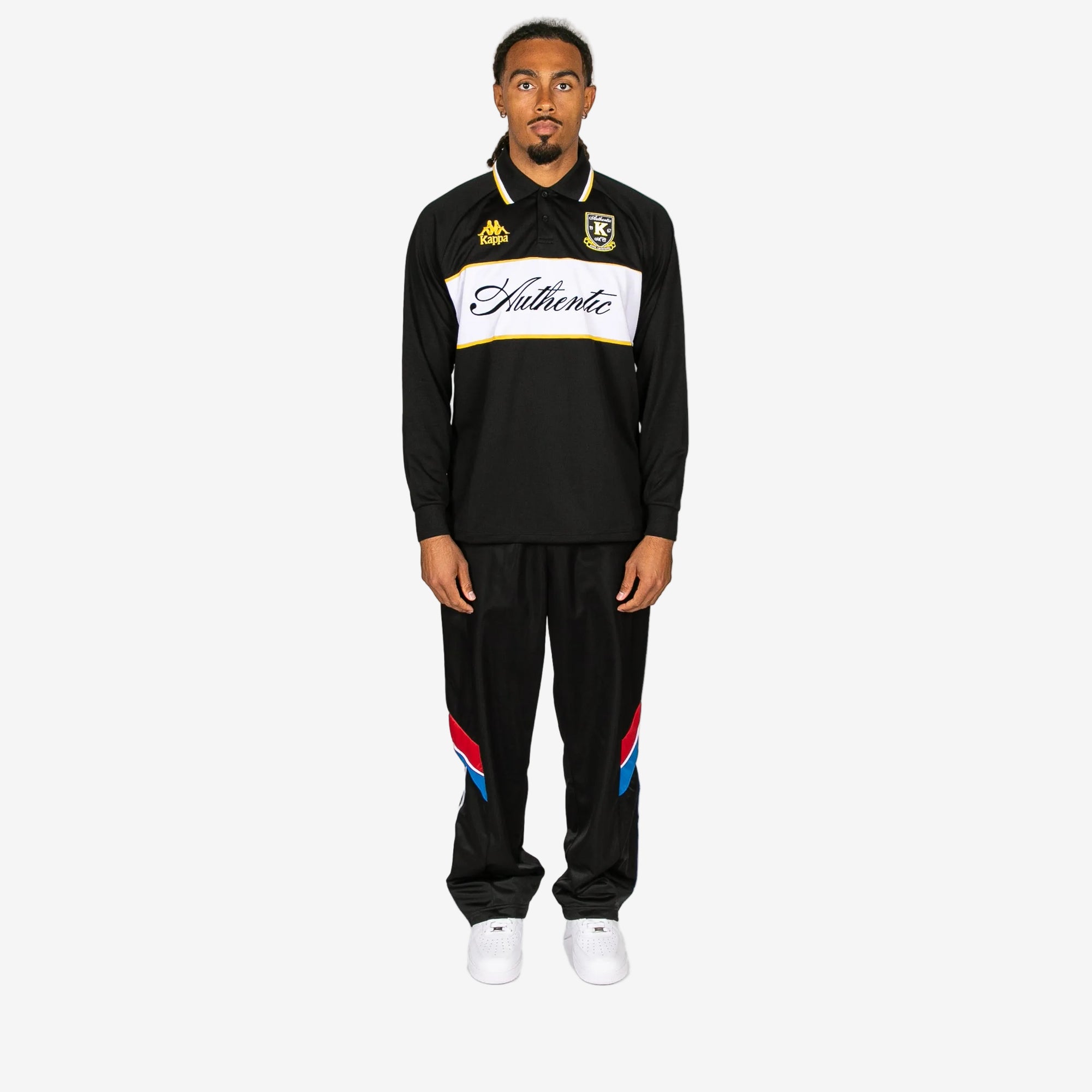 Person wearing a black tracksuit with brand logos on a white background