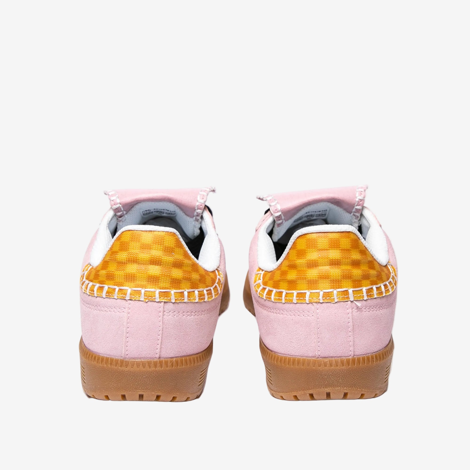 Pair of pink sneakers with yellow checkered pattern on a white background