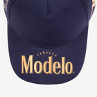 Close up of navy blue cap bill with Modelo logo in gold on the bill.