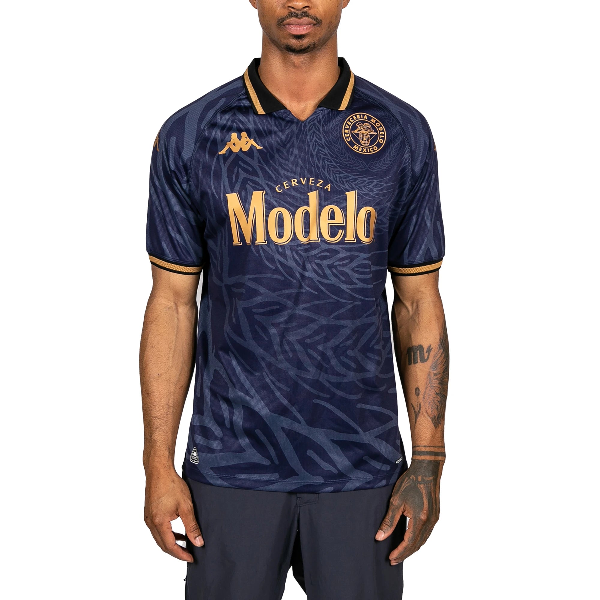 Male model wearing Kombat 2025 Modelo Soccer Jersey in navy blue and gold. Front view.