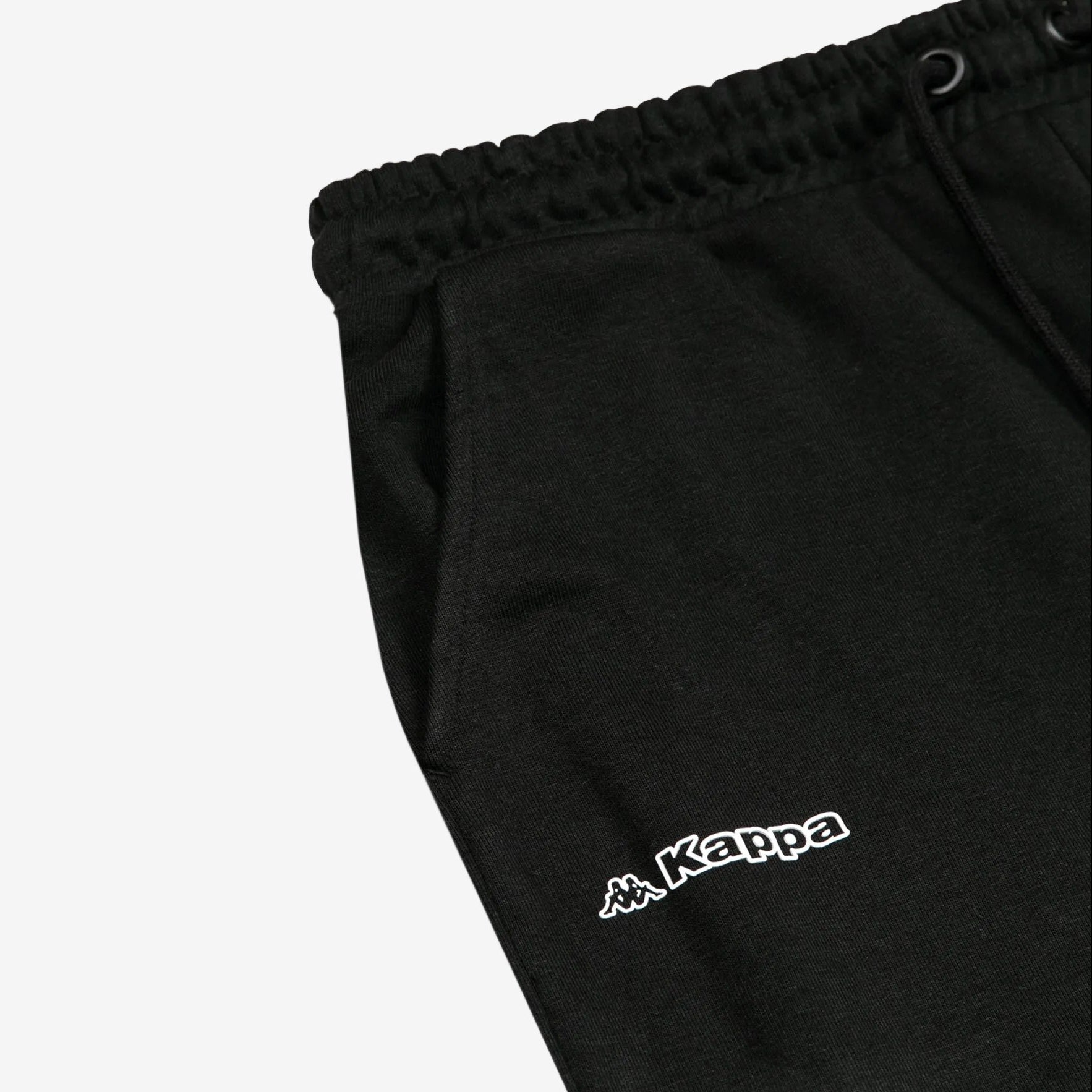 Detail view of Kappa lettering and Omini logo in white on black shorts.